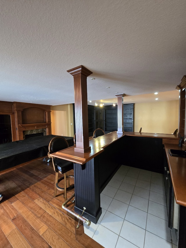 kitchen with decorative columns, open floor plan, light wood-style floors, a fireplace, and a sink