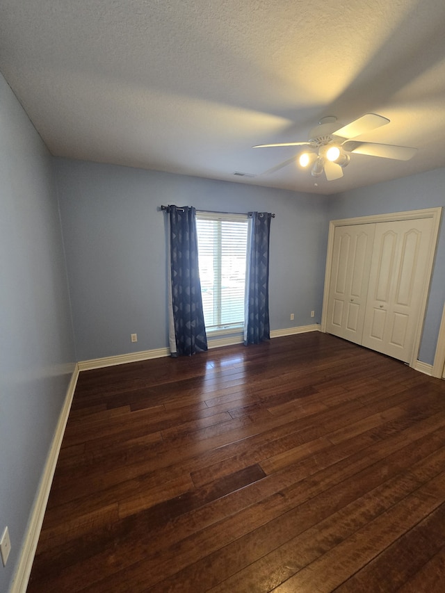 unfurnished bedroom featuring dark wood-style floors, a textured ceiling, and baseboards