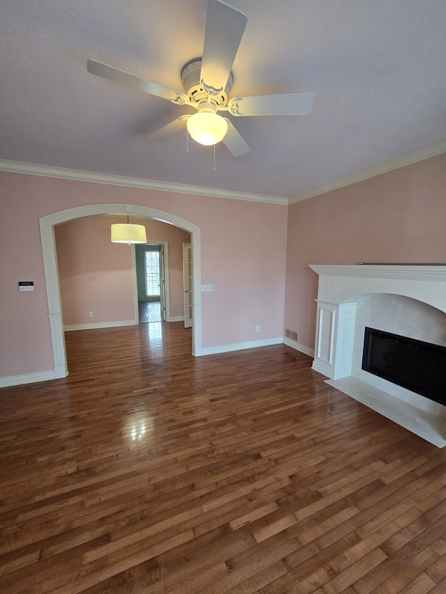 unfurnished living room featuring a fireplace with flush hearth, arched walkways, ornamental molding, and wood finished floors