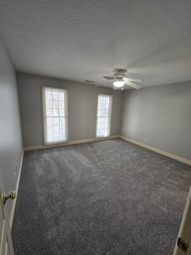 spare room featuring a textured ceiling, carpet floors, a ceiling fan, and baseboards