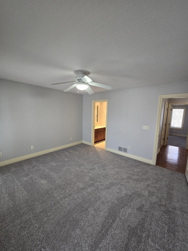 carpeted empty room with baseboards, visible vents, ceiling fan, and a textured ceiling