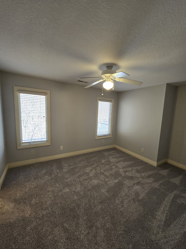 spare room with baseboards, a textured ceiling, dark carpet, and a ceiling fan