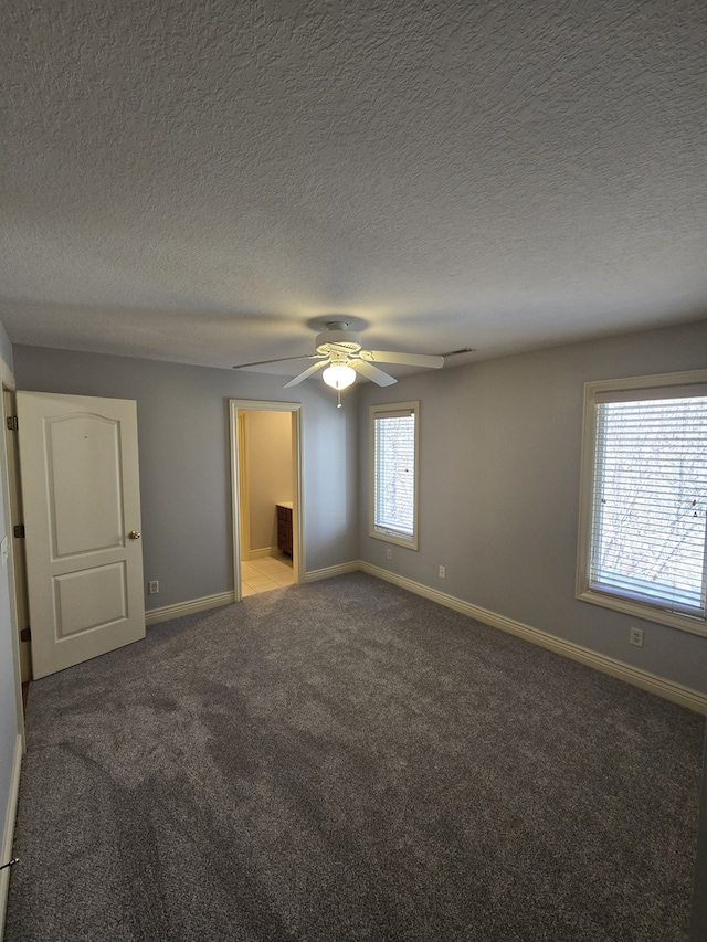 unfurnished bedroom with carpet floors, ceiling fan, a textured ceiling, and baseboards