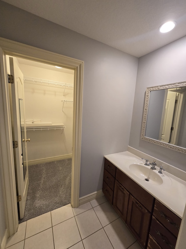 bathroom with recessed lighting, a walk in closet, vanity, and tile patterned floors