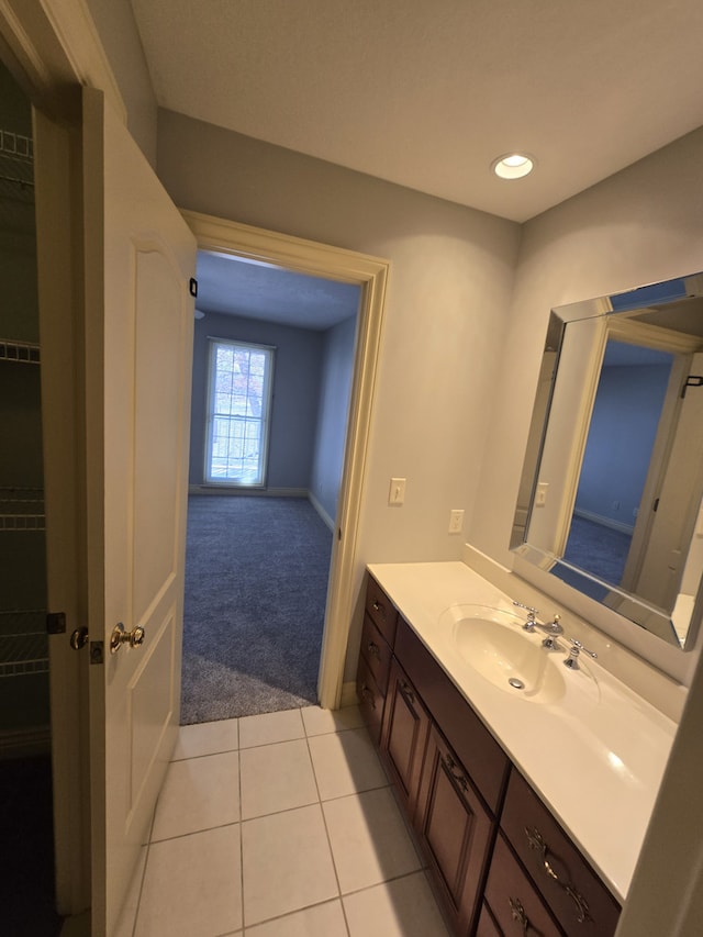 bathroom with tile patterned flooring, a walk in closet, and vanity