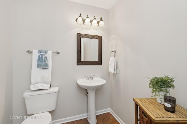 bathroom with toilet, baseboards, and wood finished floors