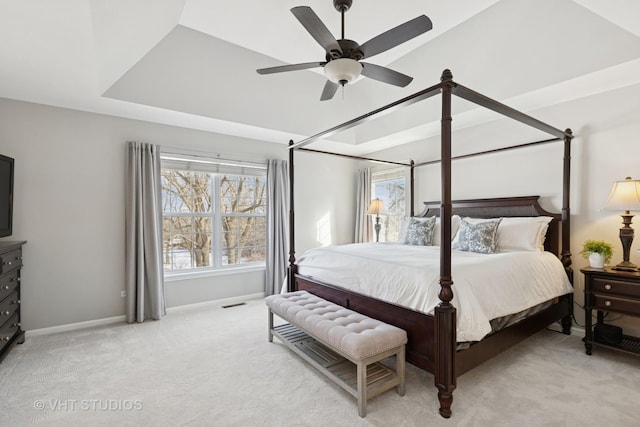 bedroom featuring light colored carpet, visible vents, baseboards, a ceiling fan, and a raised ceiling