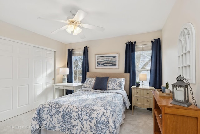 bedroom with light carpet, a ceiling fan, and a closet