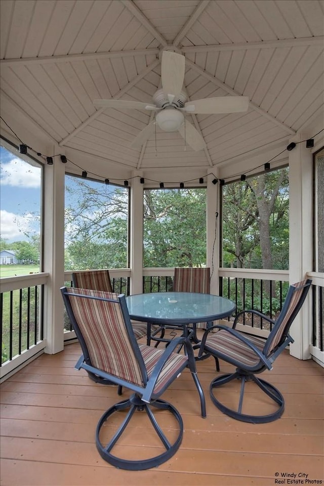 wooden deck with outdoor dining space, a ceiling fan, and a gazebo