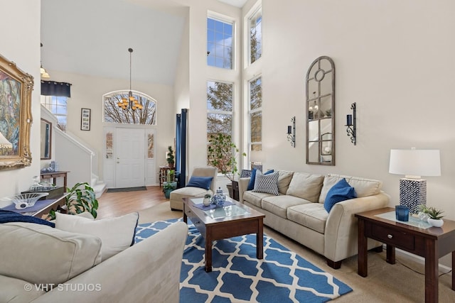 living room with an inviting chandelier, wood finished floors, a high ceiling, and stairs