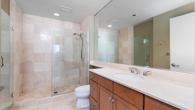 bathroom featuring visible vents, toilet, a shower stall, vanity, and tile patterned floors