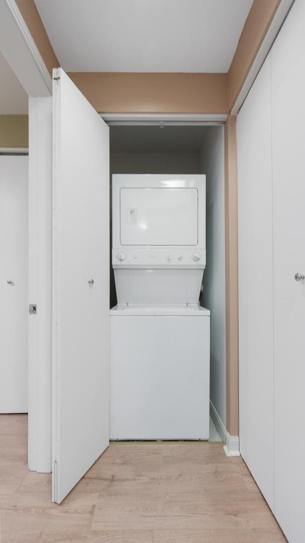 laundry area featuring stacked washer and dryer, laundry area, and light wood-style floors