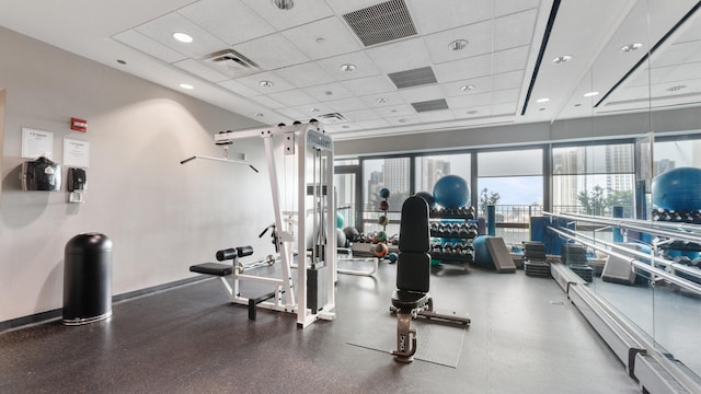 workout area with baseboards, visible vents, and a drop ceiling