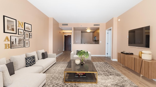 living room featuring light wood-style flooring, visible vents, and baseboards