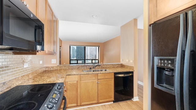 kitchen featuring black appliances, backsplash, light wood-type flooring, and a sink