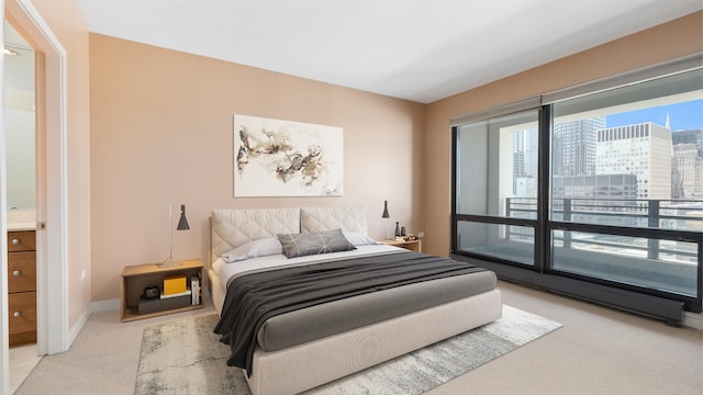 carpeted bedroom featuring access to outside, baseboards, and a city view