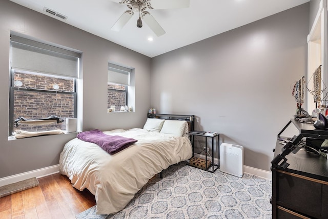 bedroom featuring ceiling fan, light wood finished floors, visible vents, and baseboards