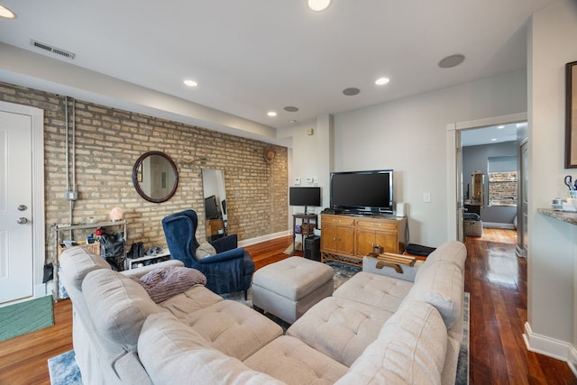 living room with recessed lighting, visible vents, brick wall, and wood finished floors