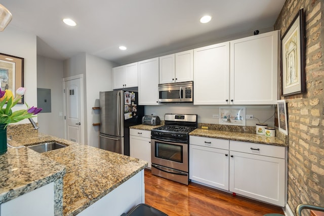 kitchen featuring white cabinets, light stone counters, stainless steel appliances, and dark wood-style flooring