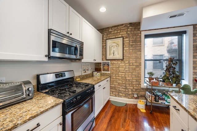 kitchen with visible vents, appliances with stainless steel finishes, dark wood-style flooring, light stone countertops, and white cabinetry