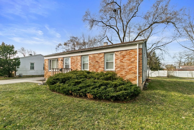 view of front of property with brick siding, a front lawn, a chimney, and fence