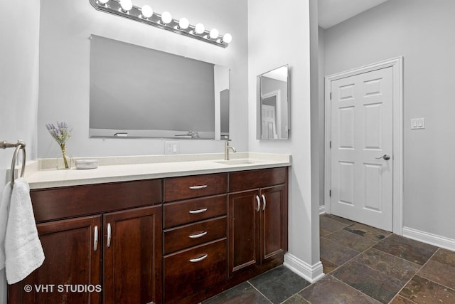 bathroom featuring stone finish flooring, baseboards, and vanity