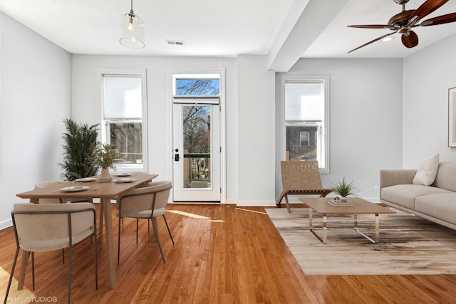 interior space with ceiling fan, wood finished floors, visible vents, and baseboards