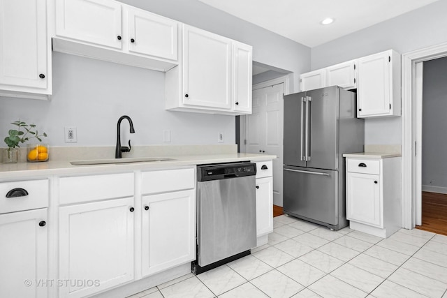 kitchen with white cabinets, stainless steel appliances, light countertops, and a sink