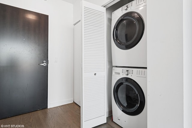 washroom featuring dark wood-type flooring, stacked washer and dryer, and laundry area