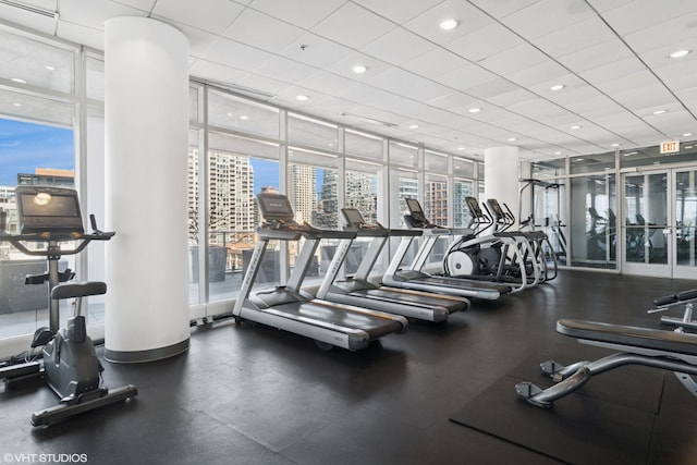 exercise room with recessed lighting, expansive windows, a view of city, and a drop ceiling