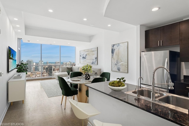 kitchen featuring recessed lighting, dark brown cabinets, freestanding refrigerator, and a sink