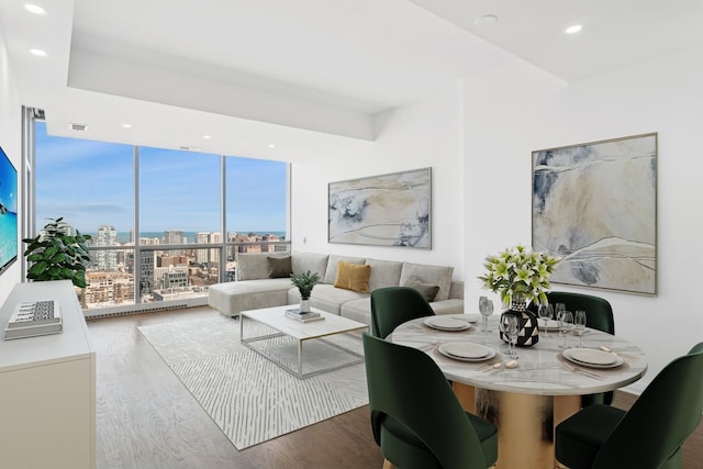 living room with visible vents, a view of city, expansive windows, wood finished floors, and recessed lighting