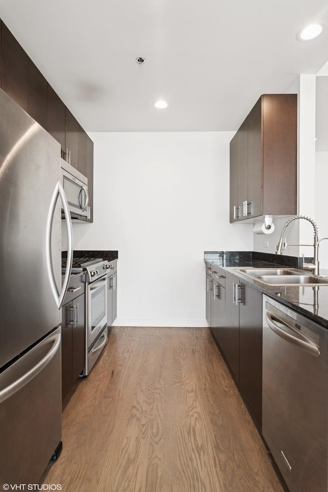 kitchen with dark wood finished floors, dark brown cabinets, appliances with stainless steel finishes, and a sink