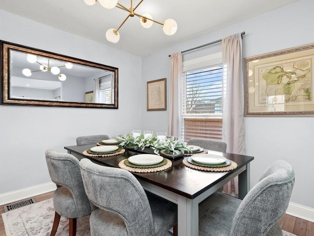 dining area featuring baseboards, wood finished floors, visible vents, and a chandelier