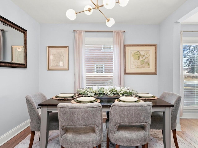 dining area featuring an inviting chandelier, wood finished floors, and baseboards