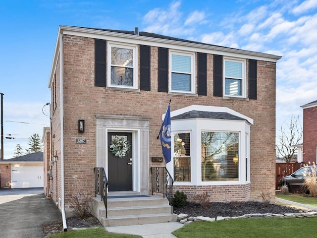 view of front facade featuring brick siding, a detached garage, and an outdoor structure