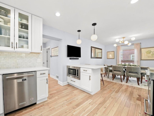 kitchen featuring decorative backsplash, appliances with stainless steel finishes, light wood-type flooring, and light countertops