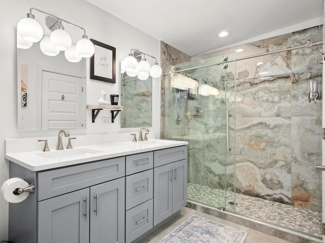 full bathroom featuring double vanity, a marble finish shower, and a sink