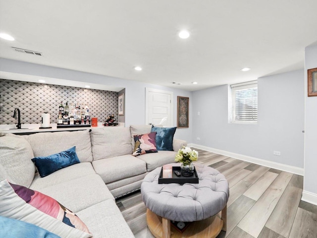 living room with visible vents, recessed lighting, baseboards, light wood finished floors, and wet bar