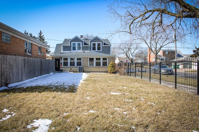 rear view of house featuring brick siding, fence, cooling unit, and a yard