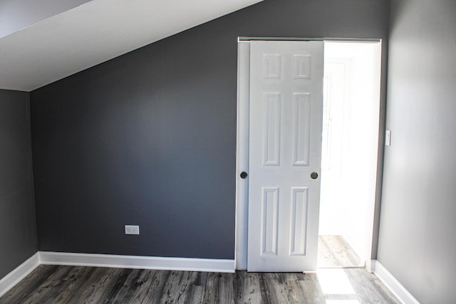 bonus room featuring lofted ceiling, dark wood-style flooring, and baseboards