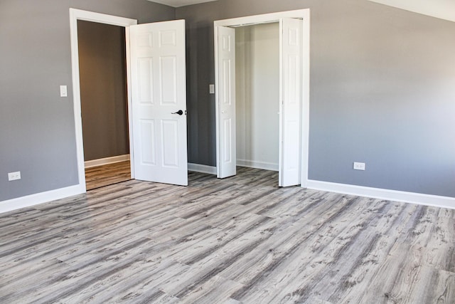 unfurnished bedroom with a closet, wood finished floors, and baseboards