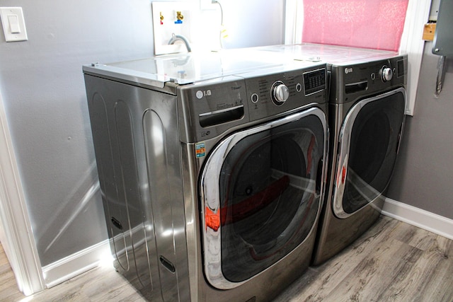 washroom featuring baseboards, laundry area, light wood-type flooring, and washer and dryer