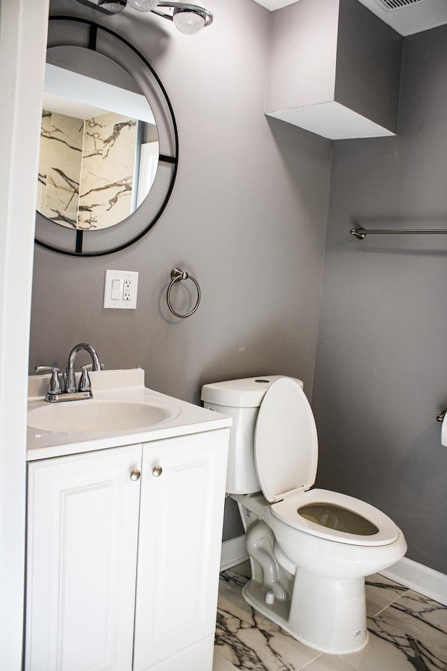 bathroom with marble finish floor, baseboards, vanity, and toilet