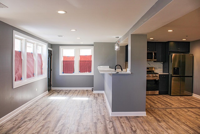 unfurnished room with recessed lighting, a sink, wood finished floors, visible vents, and baseboards