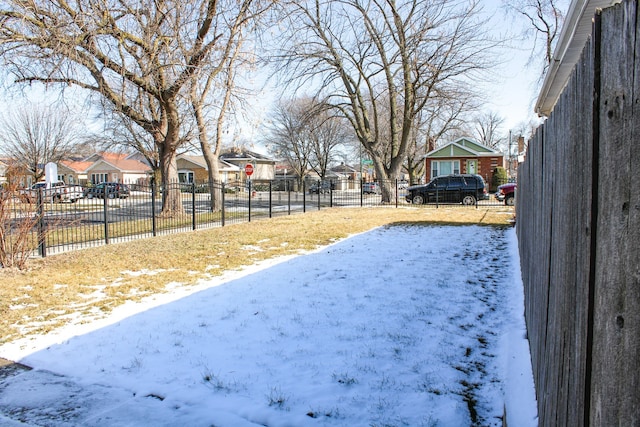 snowy yard featuring fence and a residential view