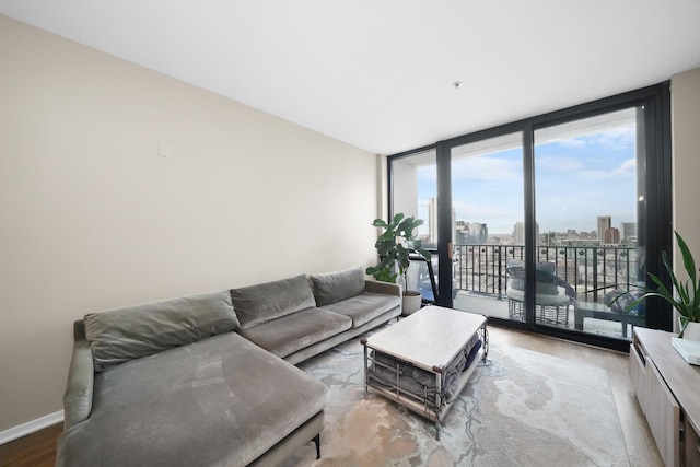 living area featuring a view of city, baseboards, a wall of windows, and wood finished floors