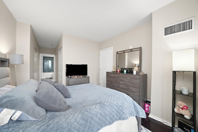 bedroom featuring visible vents, baseboards, and wood finished floors