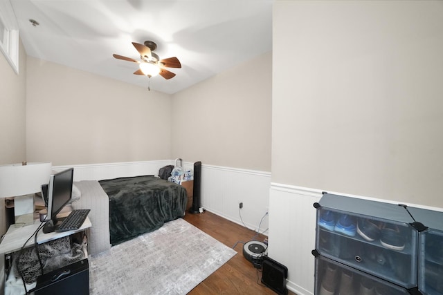 bedroom with a wainscoted wall, ceiling fan, and dark wood-type flooring