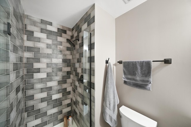 bathroom featuring toilet and a tile shower